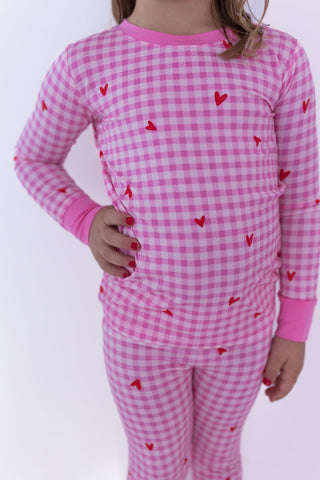 In My Jammers Two Piece Set - Be Mine Gingham
Child wearing pink gingham pajamas with red hearts on a white background