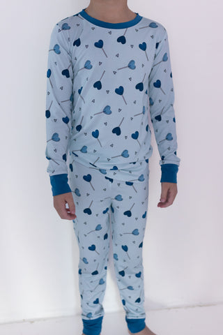 In My Jammers Two Piece Set - Blue Sugar Rush
Child wearing a blue heart-patterned pajama set against a white background