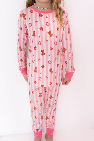 In My Jammers Two Piece Set - Love You Bear-y Much
Child wearing a pink pajama set with teddy bear and heart patterns on a white background