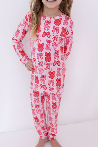 In My Jammers Two Piece Set - Valentine's Bows
Child wearing a pink onesie with red bow pattern on a white background