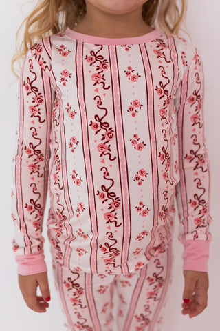 In My Jammers Two Piece Set - Vintage Love
Child wearing a pink and white patterned outfit with floral designs on a plain background