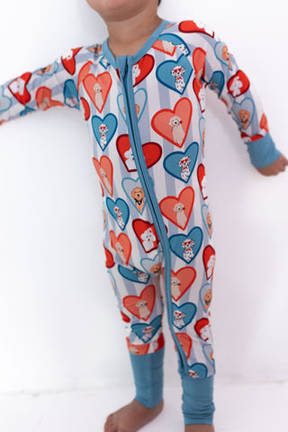 In My Jammers Zipper Romper - Blue Fur-Ever Valentine Baby wearing a colorful onesie with heart patterns on a white background