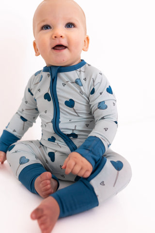 In My Jammers Zipper Romper - Blue Sugar Rush
Baby wearing a gray and blue outfit with heart patterns on a white background