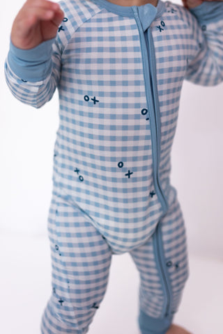 In My Jammers Zipper Romper - Blue XO Gingham
Baby wearing a blue checkered onesie with star patterns on a white background