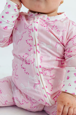 In My Jammers Zipper Romper - Cora
Baby in a pink floral outfit with a zipper on a light background