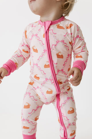 In My Jammers Zipper Romper - Fall Pie and Bows
A baby wearing a pink and white long-sleeve footless sleeper with a pink zipper and orange cake print, shown from the neck down against a white background.