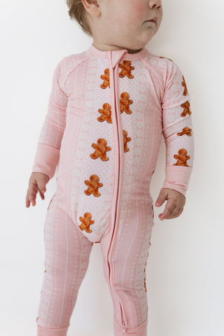 In My Jammers Zipper Romper - Gingerbread Cookies
A baby wearing a light pink footed sleeper with a vertical zipper and orange gingerbread cookie appliques, photographed against a plain white background.