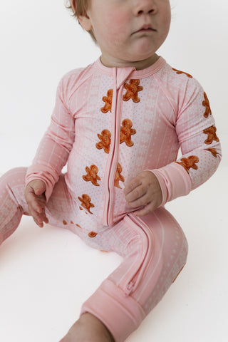In My Jammers Zipper Romper - Gingerbread Cookies
A baby wearing a pink zip-front footed sleeper with gingerbread cookie prints, sitting against a plain white background.