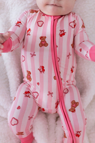In My Jammers Zipper Romper - Love You Bear-y Much
Baby in a pink and white striped onesie with teddy bear and bow patterns on a soft surface.