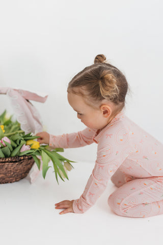 In My Jammers Zipper Romper - Pink Little Goose
Child in pink pajamas playing with flowers on a white background