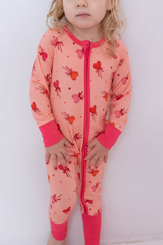 In My Jammers Zipper Romper - Pink Sugar Rush
Child wearing a pink onesie with heart patterns on a white background