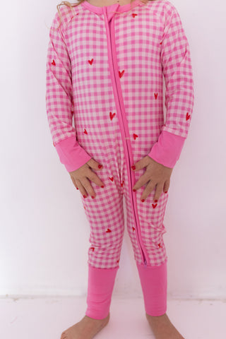 In My Jammers Zipper Romper - Be Mine Gingham
Pink checkered onesie with heart patterns on a white background