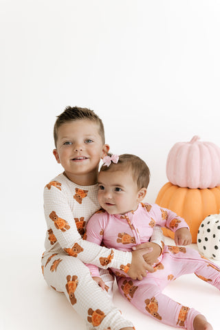 In My Jammers Zipper Romper - Polka Dot Little Boo Bear
In My Jammers Two Piece Set - Gingham Little Boo Bear
Two children sitting together in matching one-piece pajamas with a brown teddy bear print. The older child wears an off-white version, and the younger child wears a light pink version.