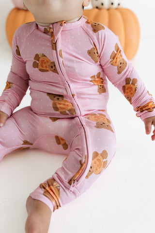 In My Jammers Zipper Romper - Polka Dot Little Boo Bear
A baby wearing a pink long-sleeve footless zip-up sleeper with a teddy bear print, sitting against a white background with pumpkins in the background.