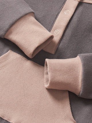 Little Bipsy Colorblock Ribbed Romper - Graphite
Close-up of a gray and beige sweater with rolled-up sleeves.