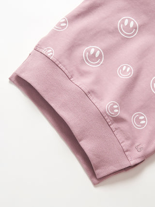 Little Bipsy Smiley Pullover - Dusty Purple
Close-up of a pink fabric with smiley face patterns on a white background