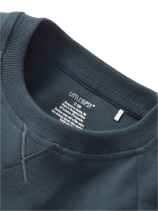Little Bipsy Pocket Pullover - Night Fall 
Close-up of a dark gray sweatshirt with 'Little Bipsy' label on a light gray background