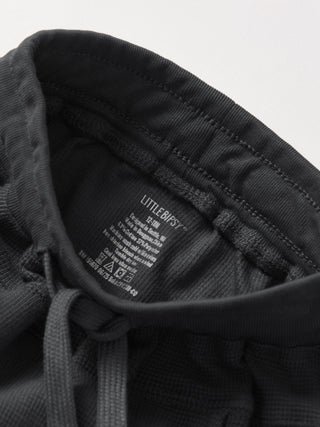 Little Bipsy Waffle Jogger - Shadow
Close-up of a black hoodie with a brand label on a light gray background