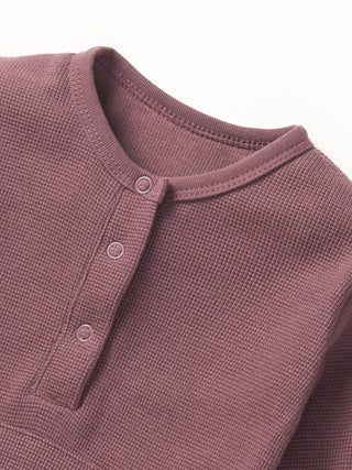 Little Bipsy Waffle Romper - Huckleberry
Close-up of a textured purple shirt with button details on a white background