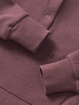 Little Bipsy Waffle Romper - Huckleberry
Close-up of a textured purple sweater with button details