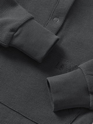 Little Bipsy Waffle Romper - Shadow
Close-up of a dark gray textured shirt with rolled-up sleeves on a matching fabric background.