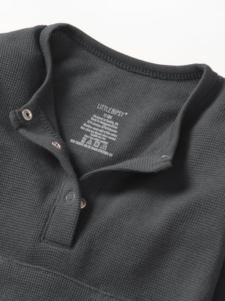 Little Bipsy Waffle Romper - Shadow
Close-up of a dark gray textured polo shirt with brand label on a white background