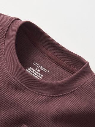 Little Bipsy Waffle Top - Huckleberry
Close-up of a brown garment with a visible brand label on a light gray background
