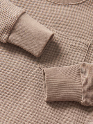 Little Bipsy Waffle Top - Mushroom
Close-up of a beige textured sweater with rolled-up sleeves.