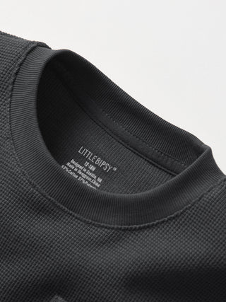 Little Bipsy Waffle Top - Shadow
Close-up of a black garment with 'LITTLE RIPSY' branding on a light gray background