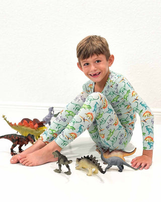 Lev Baby Pajama Set - Landon
Child wearing dinosaur-themed pajamas surrounded by toy dinosaurs on a white background