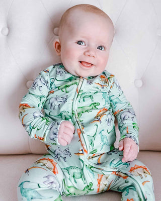 Lev Baby Zippered Footie - Landon
Baby wearing a dinosaur-patterned onesie sitting on a white cushion.