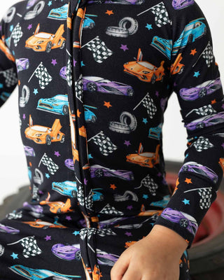 Lev Baby Poppy Convertible Zipper Romper - Elias
Children's pajama set with car pattern on a dark background