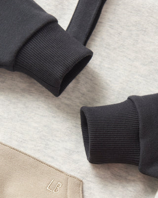 Little Bipsy Colorblock Mockneck Pullover - Stone Grey
Close-up of black sweater cuffs on a light gray fabric background