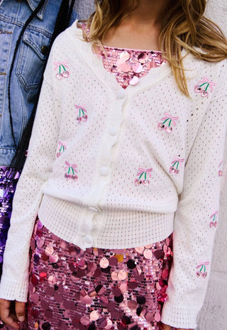 Lola and The Boys Cherry on Top Cardigan
White embroidered cardigan over a pink sequin top and skirt with denim jacket.