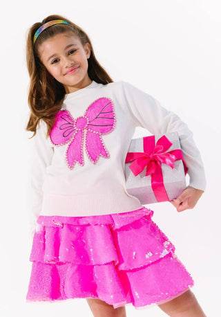 Lola and The Boys Pinky Big Bow Sweater
Child wearing a white sweater with pink bow design and a matching pink skirt on a white background