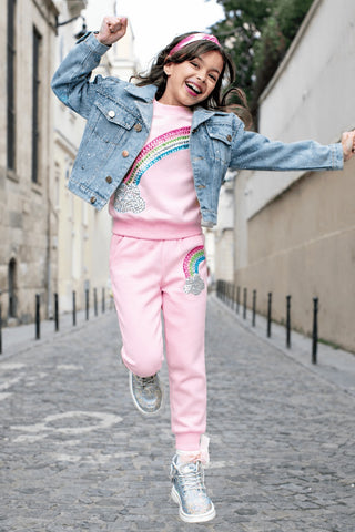 Lola and The Boys Rainbow Dreams Joggers Set
Child wearing a pink outfit with rainbow designs on a street.