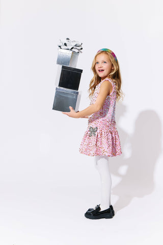 Young girl in a pink dress holding a toy elevator against a white background