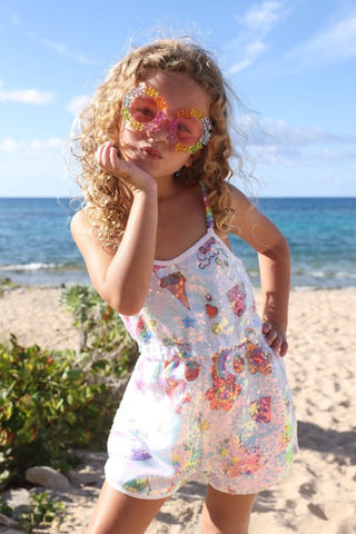 Lola and The Boys Summertime Fun Sequin Romper
Young girl in a floral dress on a beach with ocean in the background
