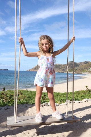 Lola and The Boys Summertime Fun Sequin Romper
Young girl on a swing by the beach with ocean and mountains in the background