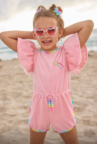 Lola and The Boys Velour Rainbow Gems Romper
Young girl in a pink outfit with rainbow details on a beach