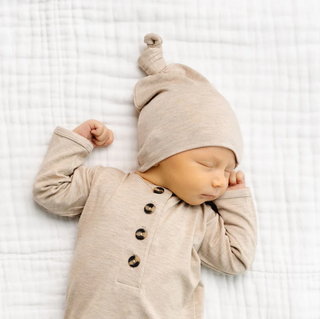 Lou Lou and Company Top Knot Hat - Ryan
Newborn baby wearing a beige outfit and hat, sleeping on a white textured blanket.