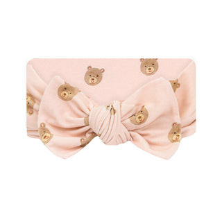 Lou Lou and Company Headband - Honey
A light pink fabric headband with a large bow at the center and a repeating pattern of small teddy bear faces, shown on a plain white background.