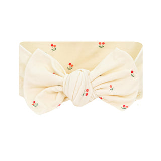 Lou Lou and Company Headband - Sadie 
A cream-colored fabric headband with a knotted bow center, decorated with small embroidered red cherry motifs with green stems, shown against a plain white background.