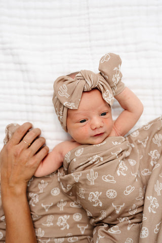 Lou Lou and Company Headband - Wyatt
Newborn baby wrapped in a brown blanket with white patterns, wearing a matching headband.