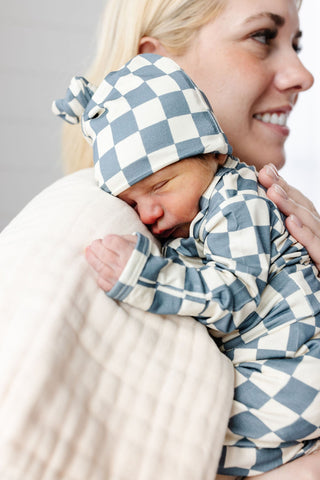 Lou Lou and Company Knotted Gown - Miles
Woman holding a baby wrapped in a checkered blanket with a matching checkered hat.