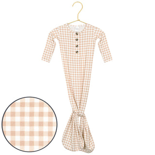 Lou Lou and Company Knotted Gown - Milo
A baby long-sleeve romper in a beige and white gingham check pattern, hanging on a gold hanger against a white background, with a circular inset showing a close-up of the fabric pattern.