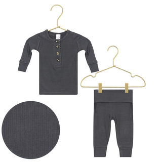 Lou Lou and Company Ribbed Top and Bottoms - Hudson
A baby two-piece outfit set consisting of a long-sleeve henley top and matching pants, both in a slate blue fabric with a small multicolor geometric pattern. The set is displayed on gold-colored hangers against a plain white background, with a circular zoom-in detail of the pattern shown in the bottom-left corner.