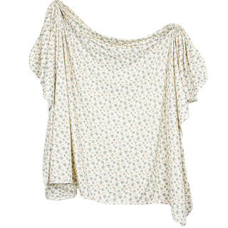 Lou Lou and Company Swaddle Blanket - Faye 
A loose, draped short-sleeve blouse with a small-scale floral and botanical print in muted green and beige on an off-white base, shown against a plain white background.