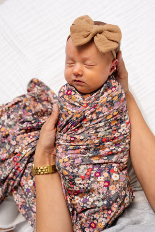Lou Lou and Company Swaddle Blanket - Gracie
Newborn baby wrapped in a floral swaddle with a large bow on a white background