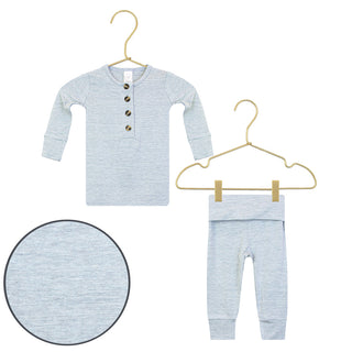 Lou Lou and Company Top and Bottoms - Crew
A baby two-piece loungewear set in light heather gray, featuring a long-sleeve henley top with three buttons and matching pants, displayed on gold hangers with a circular fabric detail inset.